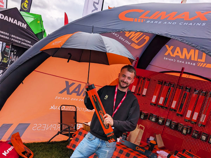 Climax Bars & Chains representative greeting visitors under their 4x4m Sealed Air Spider Dome X1 at GroundsFest, with branded orange and black canopy visible behind.