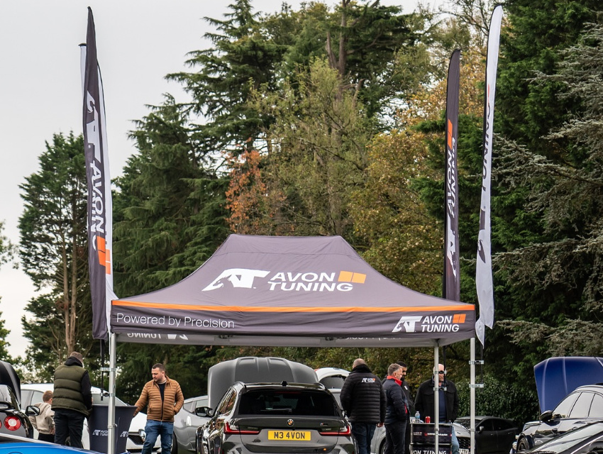 Gazebo mounted feather flags on Avon Tuning Hex 50 setup at busy outdoor automotive event
